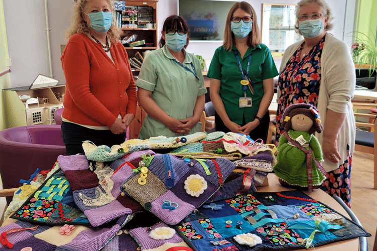 Newton Abbot WI’s Karen Jenks presents Dementia Fiddle Blankets for patients at Cheetham Hill Ward at Torbay Hospital to members of the staff there.