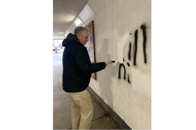 Councillor David Cox covers over the offensive graffiti and has clubbed together with other councillors to add to the reward to catch the culprits.