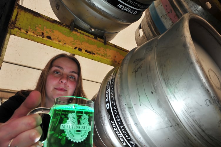 MDA18042A_SP001 Photo: Steve Pope
Setting up for the 29th Maltingsfest Beer Festival in Newton Abbot. Maltingsfest commitee member Daisy Dedman inspects a glass of Sign of Spring - a green-coloured ale from Wiltshire brewery Stonehenge Ales