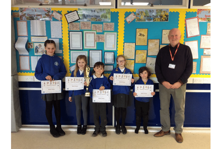John Marsh of Ipplepen History Group presents prizes to students at Ipplepen School