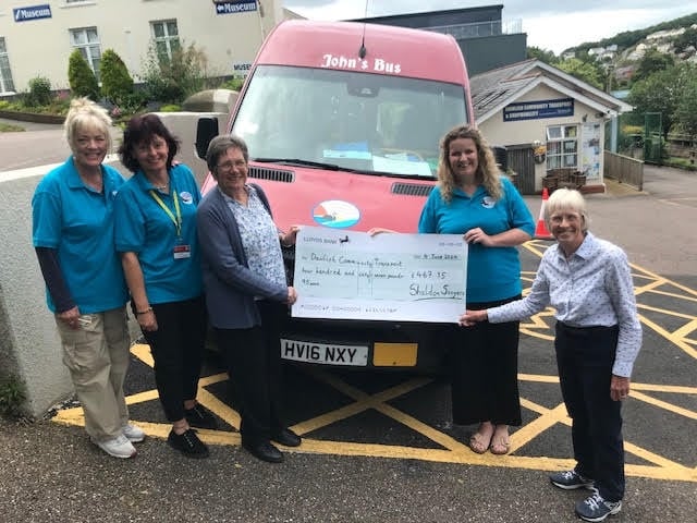 Dawlish Community Transport staff receive the cheque from The Shaldon Singers. Pictured here  Sally-Anne Bartley, Sally Preston and Fritha Langdell from DCT with Ann Pardoe (Shaldon Singers chairman) and Mary Mears (treasurer).