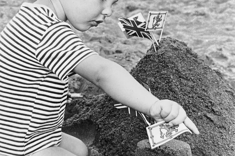 Castles in the sand. Two year old David Travis keeps busy during Shaldon Water Carnival's sand castle competition in August 1973