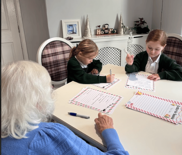 Residents at The White House care home help pupils at Our Lady and St Patrick RC Primary school to write their letters to Santa.