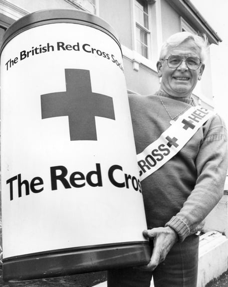 Red Cross Week 1986 in Newton Abbot and appeal organiser Leslie Scull manhandles a beast of a collecting tin 