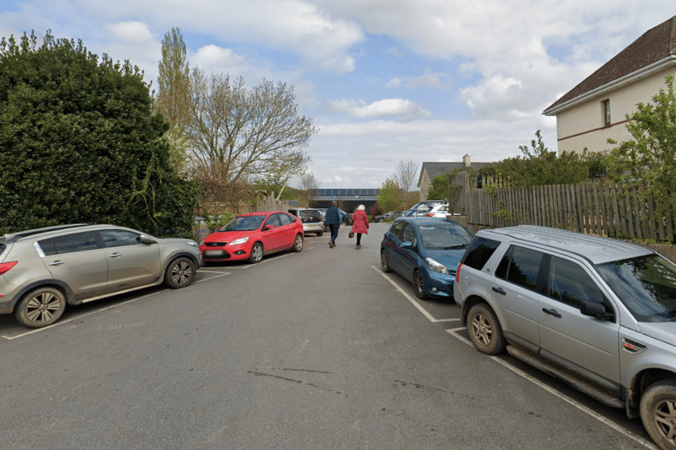 The site is located beside the access road to the village hall, adjacent to an existing car park