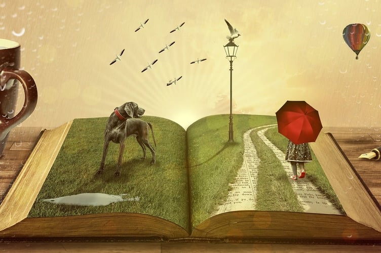 Open book with imagery of grass, a dog, a lampost, and a girl walking with a red umbrella.