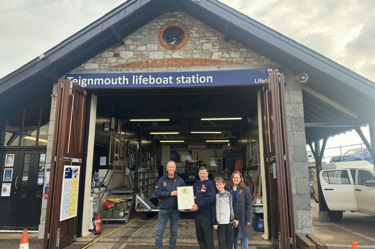 Former Teignmouth RNLI helm Humphrey Vince, accompanied by his wife Jenna and son Charlie, received his framed certificate from Teignmouth RNLI lifeboat operations manager Andy Lilburn.