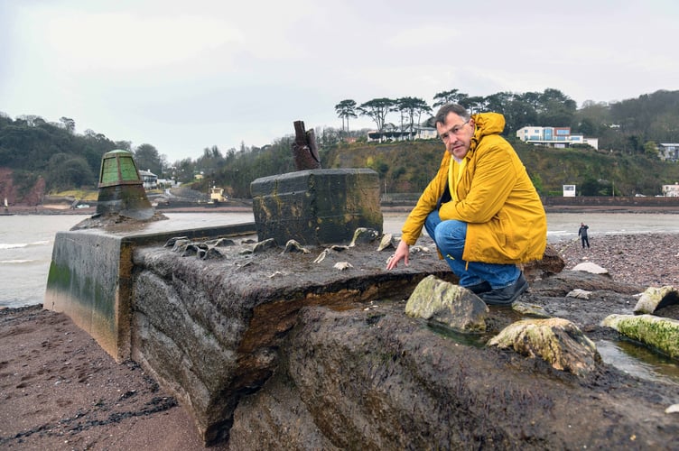 Martin Wrigley wearing his trademark yellow scarf along with a yellow jacket sitting by the Teignmouth breakwater crack