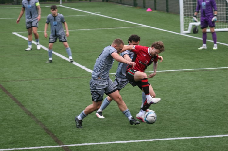 Cal Leech looks to fend off two Holsworthy defenders